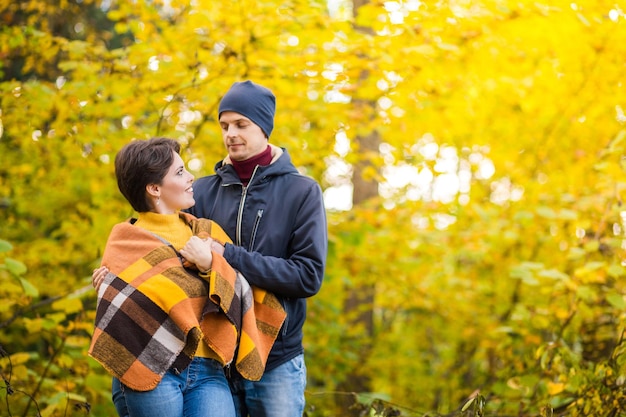 Porträt eines romantischen Paares im Herbst Stadtpark Mann und Frau posieren zwischen gelben Blättern Frau sind mit einem warmen Schal bedeckt