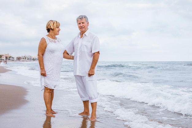 Porträt eines romantischen Seniorenpaares, das am Strand gegen den Himmel steht