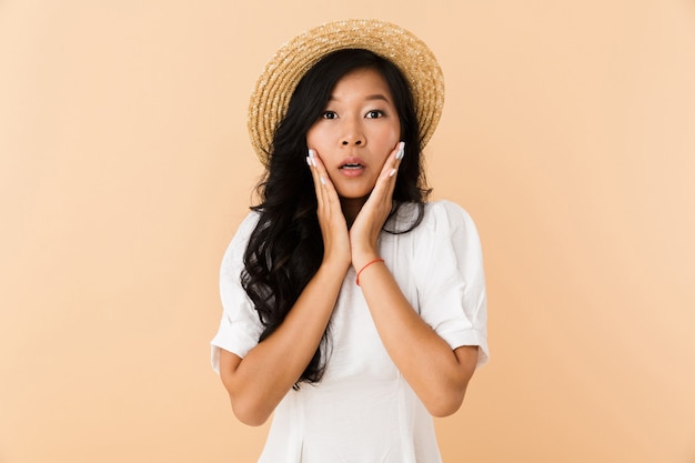 Porträt eines schockierten asiatischen Mädchens im Sommerhut
