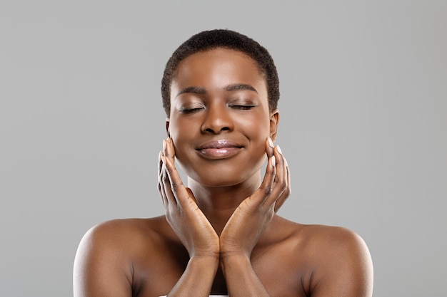 Porträt eines schönen Afro-Mädchens, das ihre perfekte Haut im Gesicht berührt