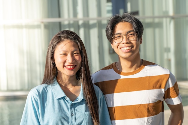 Porträt eines schönen asiatischen Paares, das an einem sonnigen Tag im Freien auf dem Studentencampus lächelt