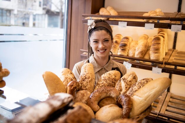 Porträt eines schönen Bäckereiverkäufers, der mit frischem Gebäck und Brot arbeitet