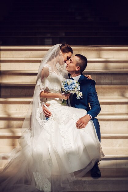 Porträt eines schönen Hochzeitspaares. Schöne Hochzeit. Der Bräutigam sitzt auf der Treppe, die Braut sitzt auf seinem Knie.