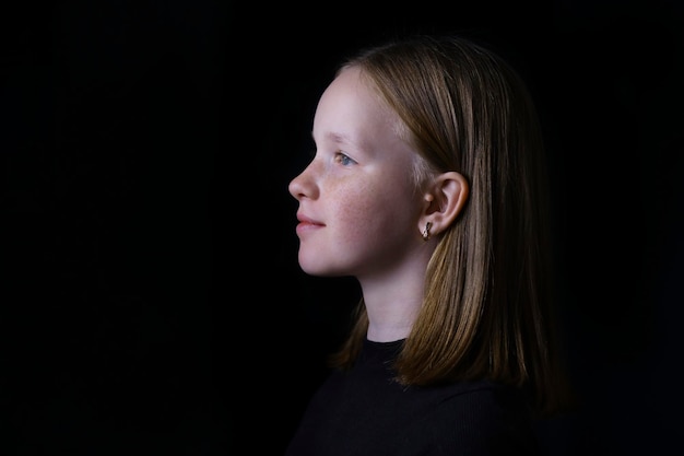 Porträt eines schönen hübschen Mädchens auf dunkelschwarzem Hintergrund Close Up Profilporträt eines jungen Mädchens.