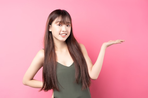 Porträt eines schönen jungen asiatischen Mädchens, das auf einer rosa Wand aufwirft
