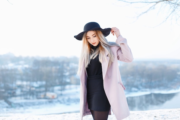 Porträt eines schönen jungen Mädchens in einem stilvollen Hut und Mantel an einem sonnigen Wintertag