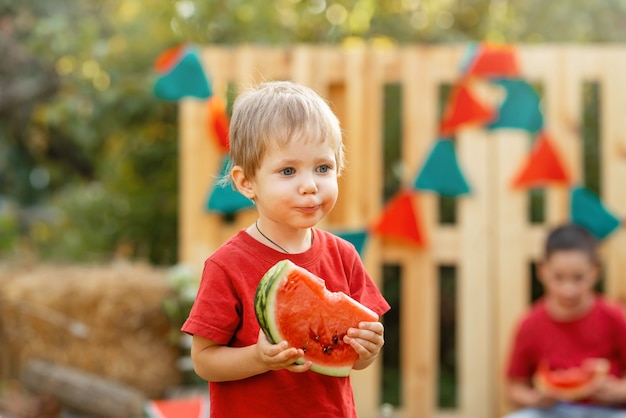 Porträt eines schönen Jungen mit Wassermelone am Sommertag