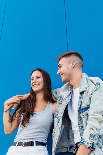 Porträt eines schönen jungen verliebten Paares, das mit blauer Wand und Kopienraum lächelt