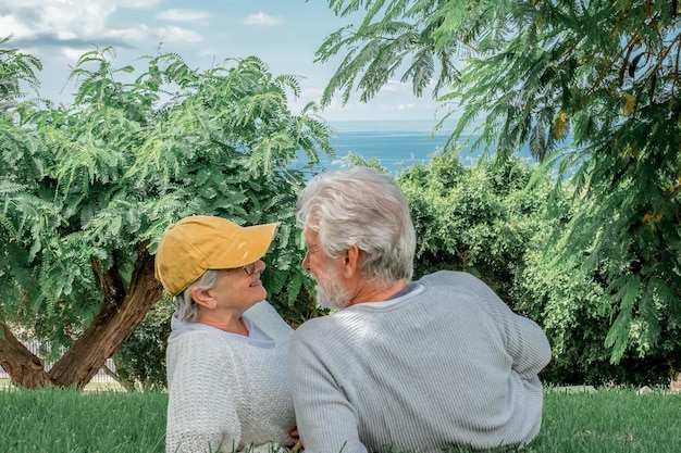 Porträt eines schönen kaukasischen Seniorenpaares, das auf der Wiese des öffentlichen Parks liegt und sich entspannt und redet Ein glückliches älteres Ehepaar verbringt angenehme Zeit zusammen im Freien