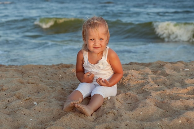 Porträt eines schönen kleinen Mädchens im Sand an der Küste