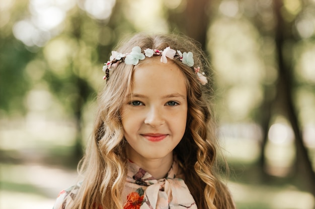 Porträt eines schönen kleinen Mädchens mit langen blonden Haaren im Park im Sommer