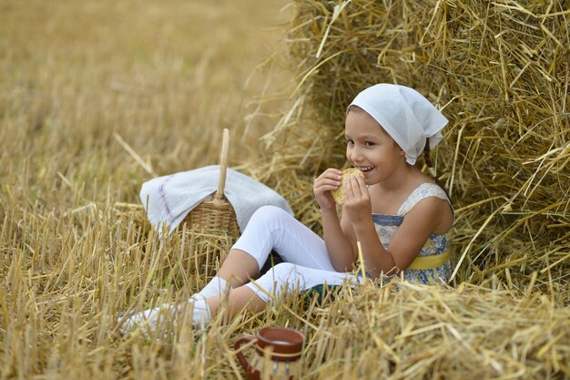 Porträt eines schönen kleinen Mädchens mit Milch und Krapfen im Feld im Sommer