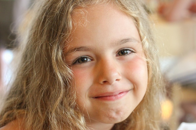 Foto porträt eines schönen lächelnden kleinen mädchens hübsches kind mit blonden locken, die auf die kamera in der nähe schauen