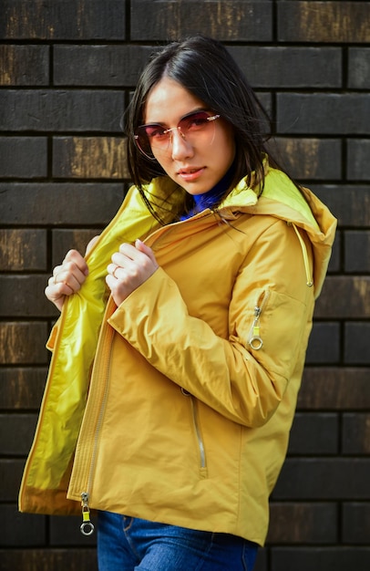 Porträt eines schönen Mädchens im Herbstjacken-Model, das in die Kamera blickt Outdoor-Lifestyle-Modeporträt, das auf der Herbststadt spazieren geht Tragen Sie stilvolle, helle Oberbekleidung, trendiges Mädchen mit Brille