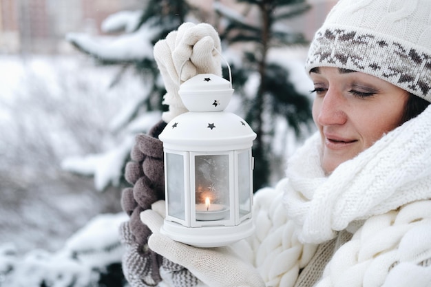 Porträt eines schönen Mädchens im Winter im Parkin ihren Händen hält sie eine Laterne mit Kerzen