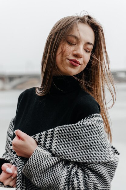 Porträt eines schönen Mädchens in einem schwarzen Pullover und einem grauen Mantel