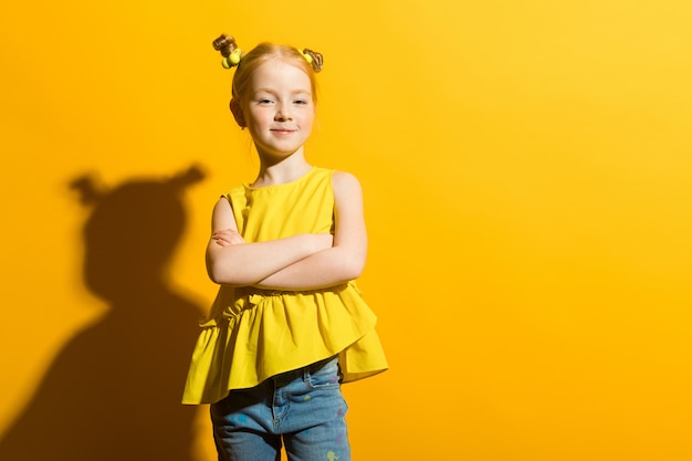 Porträt eines schönen Mädchens in einer gelben Bluse und in Blue Jeans.