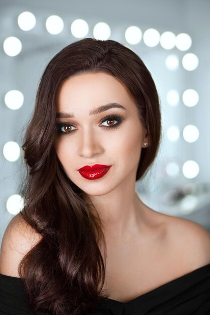 Porträt eines schönen Mädchens mit leuchtend roten Lippen und schönem Haar vor einem Hintergrund von Bokeh-Lichtern im Schönheitssalon