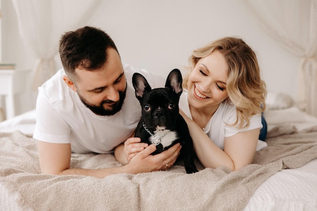 Porträt eines schönen Paares und eines französischen Hundes im Bett