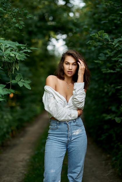 Porträt eines schönen sexy Mädchens in einem aufgeknöpften weißen Hemd im Wald Das Konzept der Menschen