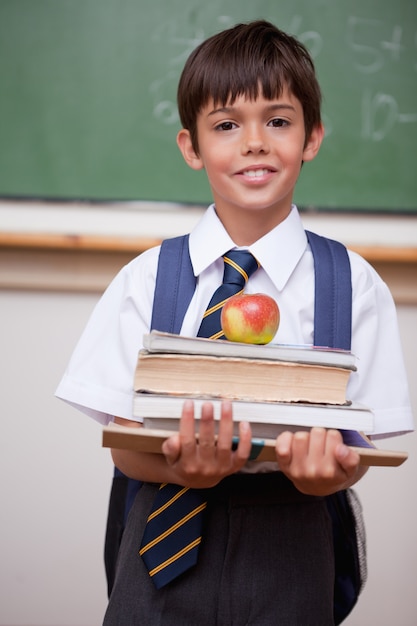 Porträt eines Schülers, der Bücher und einen Apfel hält