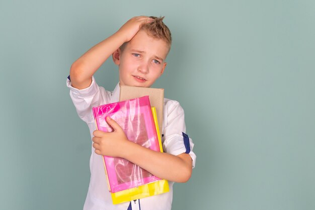 Porträt eines Schuljungen mit Büchern in der Nähe der Tafel mit verschiedenen Emotionen trauriger Schüler