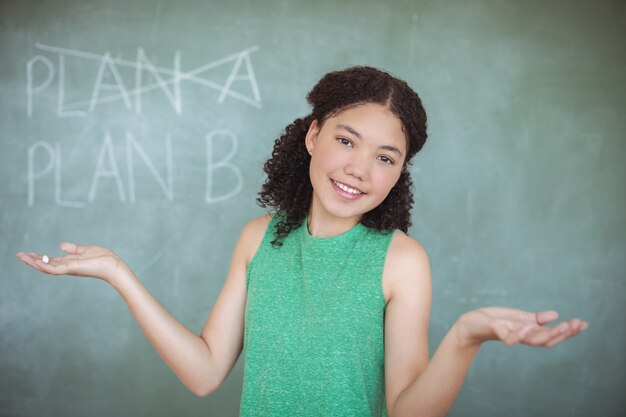 Porträt eines Schulmädchens, das gestikuliert, während es vorgibt, ein Lehrer im Klassenzimmer zu sein