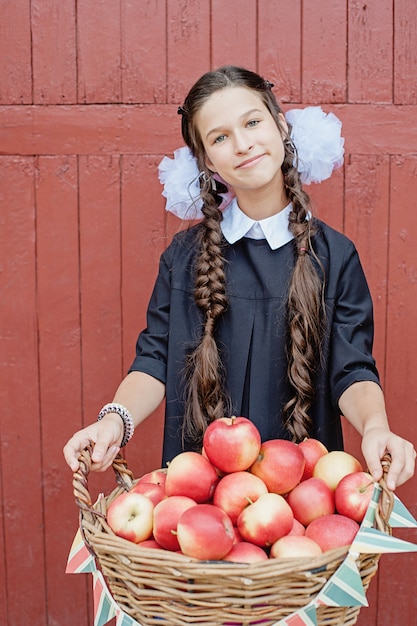 Porträt eines Schulmädchens, das mit Apfel auf Kopf steht