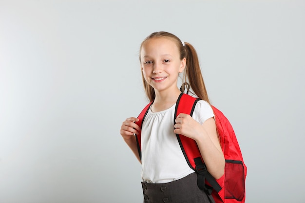 Porträt eines Schulmädchens mit Rucksack und Briefpapier