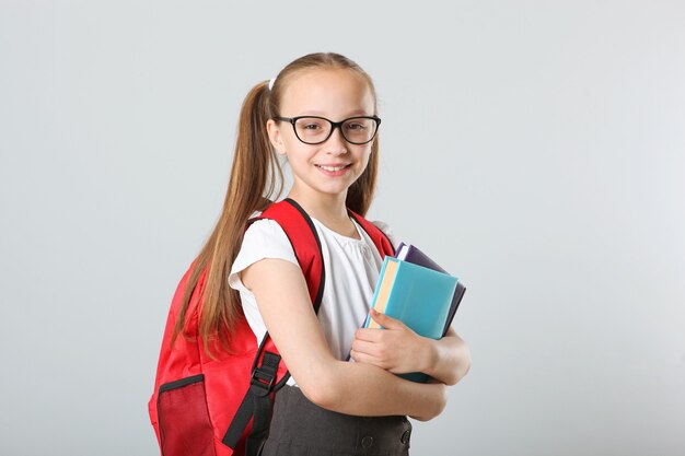 Porträt eines Schulmädchens mit Rucksack und Briefpapier