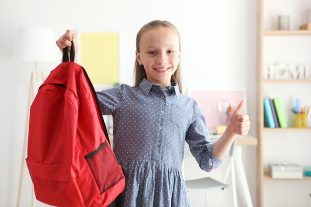 Porträt eines Schulmädchens mit Rucksack und Briefpapier