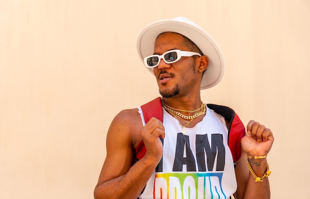Porträt eines schwulen schwarzen ethnischen Mannes auf der Pride-Party auf einer cremefarbenen LGBT-Flagge an der Wand