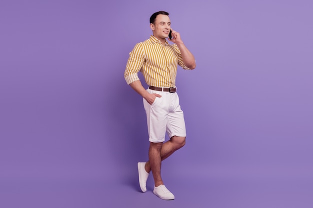 Porträt eines selbstbewussten Geschäftsmanns, der Telefon auf violettem Hintergrund spricht