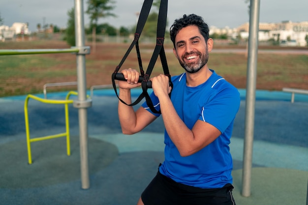 Porträt eines selbstbewussten kaukasischen Mannes während des Trainings mit Federung TRX auf der Straße