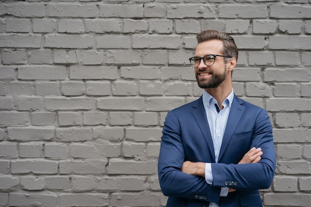 Porträt eines selbstbewussten lächelnden Managers, der eine Business-Anzugbrille trägt, isoliert auf grauem Hintergrund