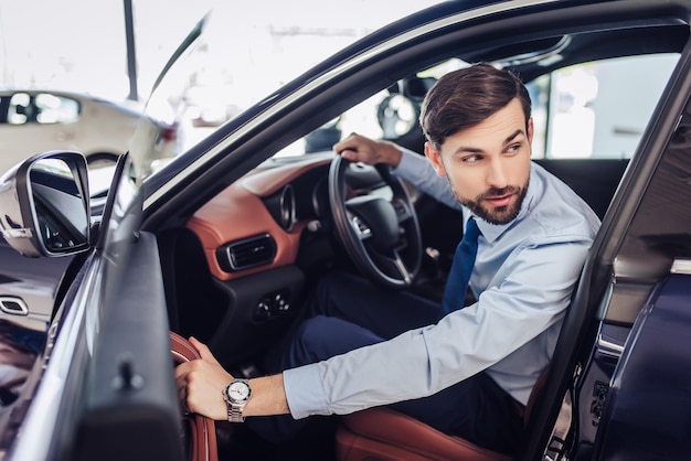 Porträt eines seriösen Geschäftsmannes, der die Fahrertür des Autos schließt