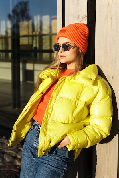Porträt eines stilvollen Mädchens mit gelbem Puffer und orangefarbener Strickmütze
