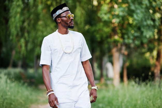 Porträt eines stilvollen und reichen schwarzen Afroamerikaners auf weißer Kleidung, Sonnenbrille und Hut