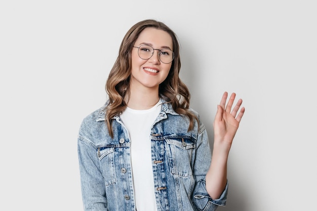 Porträt eines Studentenmädchens mit Brille, das isoliert auf weißem Hintergrund in die Kamera blickt