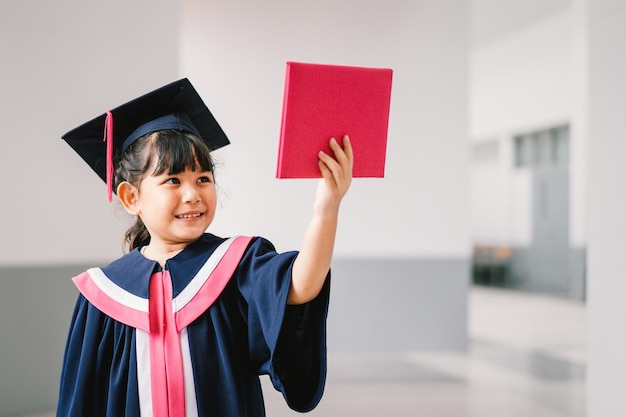 Porträt eines süßen asiatischen Schulmädchens mit Abschlusskleid in der Schule