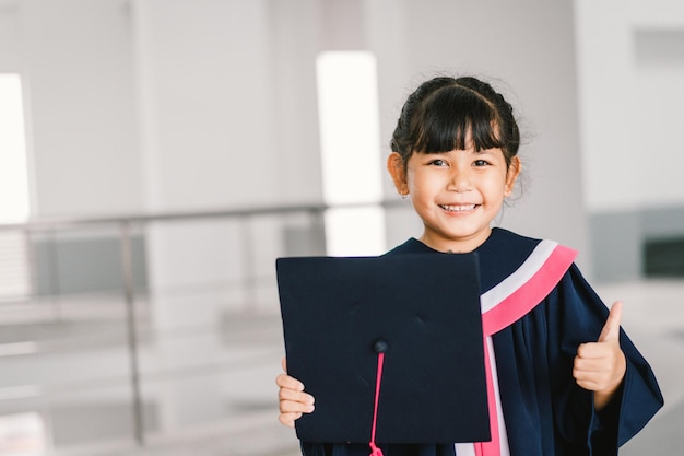 Porträt eines süßen asiatischen Schulmädchens mit Abschlusskleid in der Schule