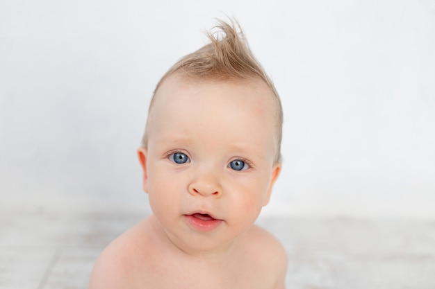 Porträt eines süßen Babys auf weißem Hintergrund mit einer Frisur und großen blauen Augen lächelnd