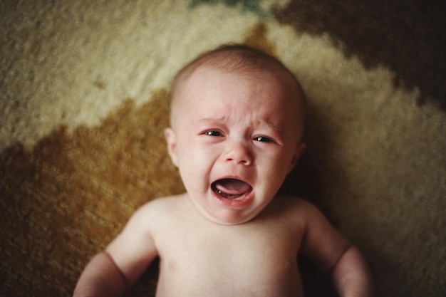 Porträt eines süßen Babys, das zu Hause im Bett weint