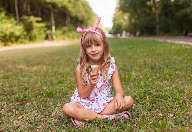 Porträt eines süßen blonden kleinen Mädchens mit Eis auf einem Spaziergang im Park.