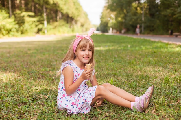 Porträt eines süßen blonden kleinen Mädchens mit Eis auf einem Spaziergang im Park.
