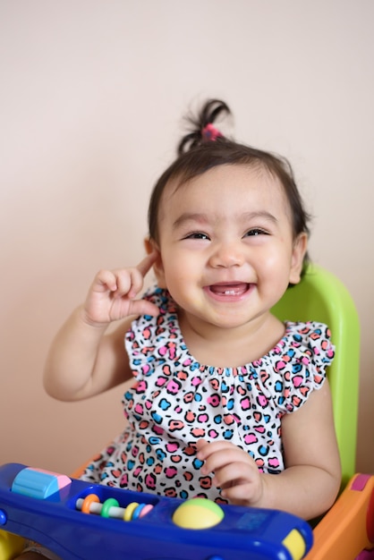 Porträt eines süßen, glücklichen kleinen asiatischen Mädchens, das ein buntes Hemd trägt, das vor kurzem Milchzähne lachte und herausschaute, Babyausdruck