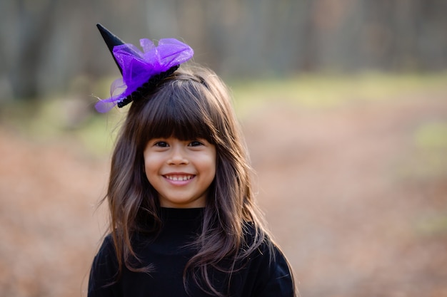 Porträt eines süßen indischen Mädchens in einem Hexenkostüm im Herbstwald für Halloween-Raum für Text