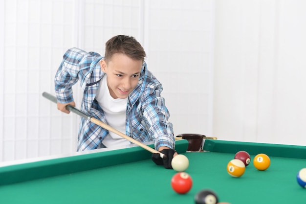 Porträt eines süßen Jungen, der Billard spielt