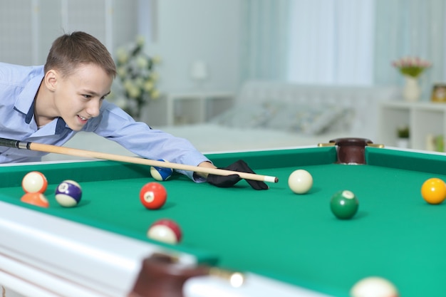 Porträt eines süßen Jungen, der Billard spielt