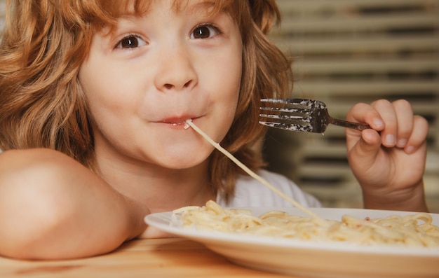 Porträt eines süßen Jungen, der Pasta Spaghetti isst Nahaufnahme des kaukasischen Kindergesichts Nahaufnahmekopf eines lustigen Kindes
